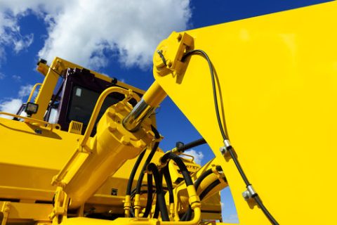 Bulldozer, huge yellow powerful construction machinery with big bucket, focused on hydraulic piston arm, blue sky and white clouds on background